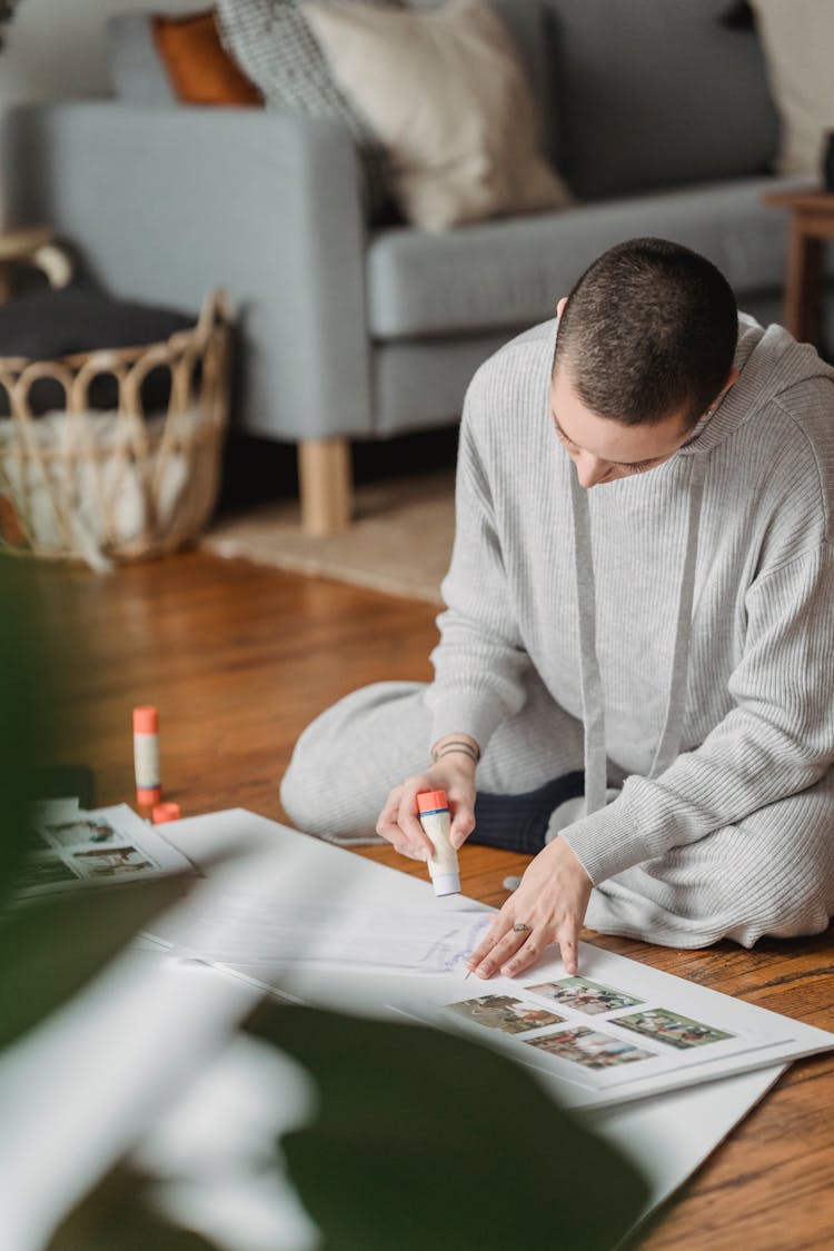 Unrecognizable Person With Glue Compiling Photography Collage In House