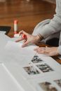 Crop woman with glue creating photo collage on floor