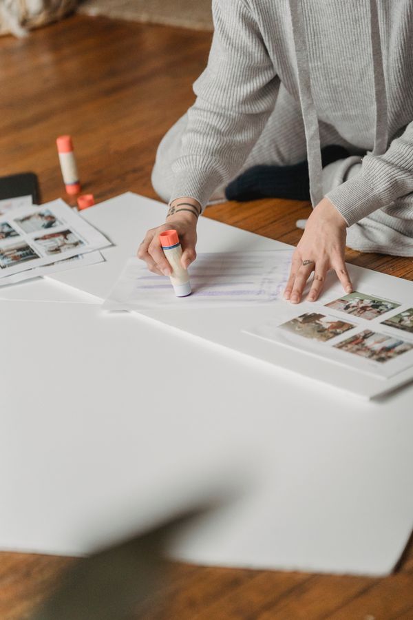 Anonymous woman gluing photos on papers