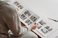 Crop unrecognizable woman looking through printed photos in album