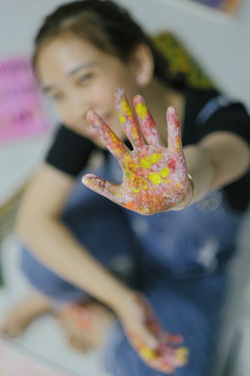 Crop happy girl showing hand in finger paints