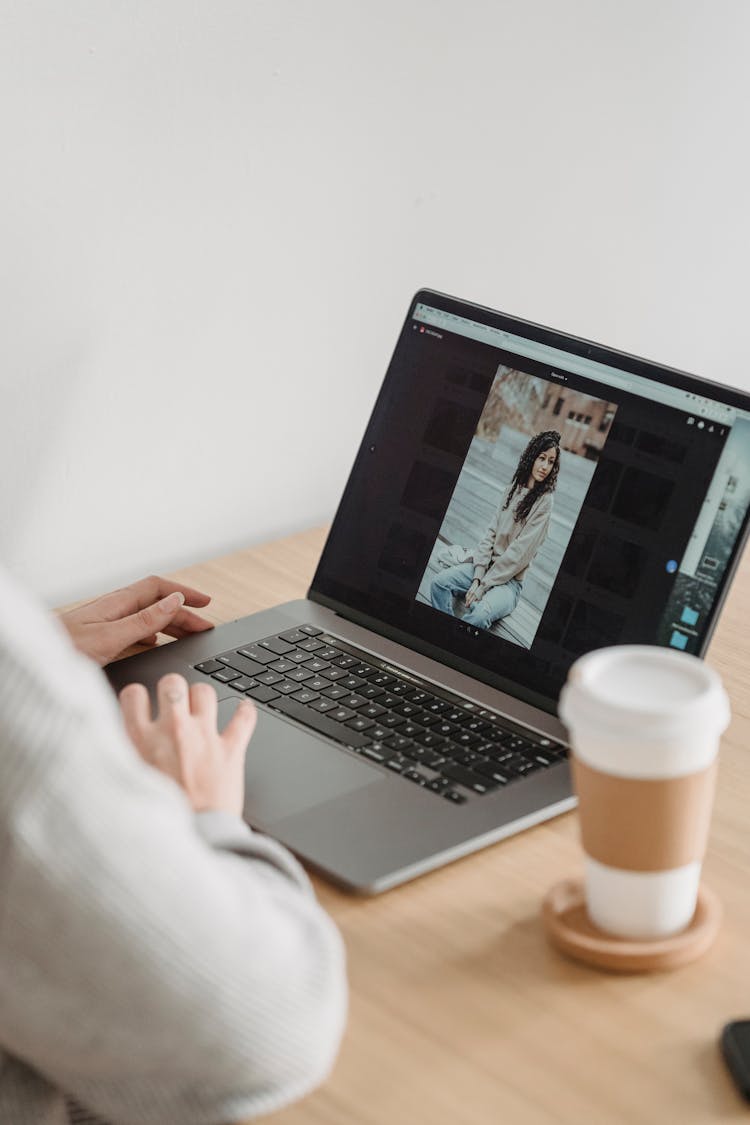 Crop Faceless Person Looking At Photos On Laptop