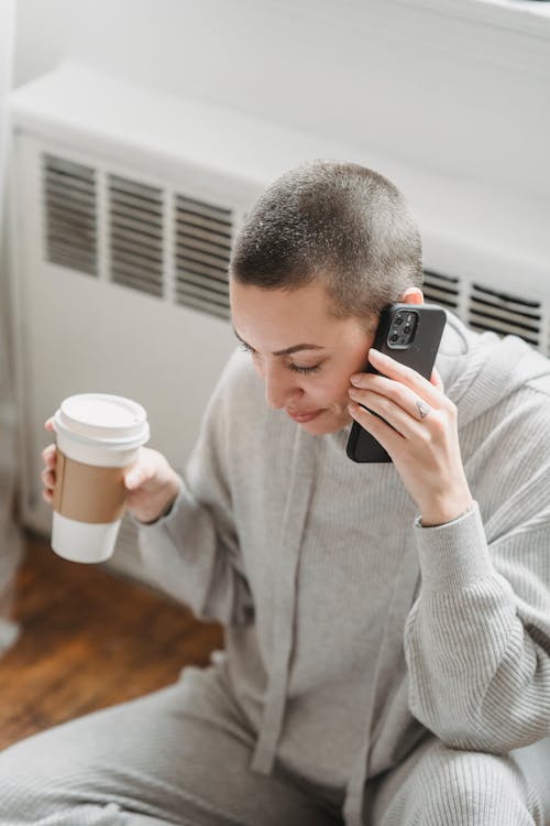 Free Woman with coffee talking on phone near window Stock Photo