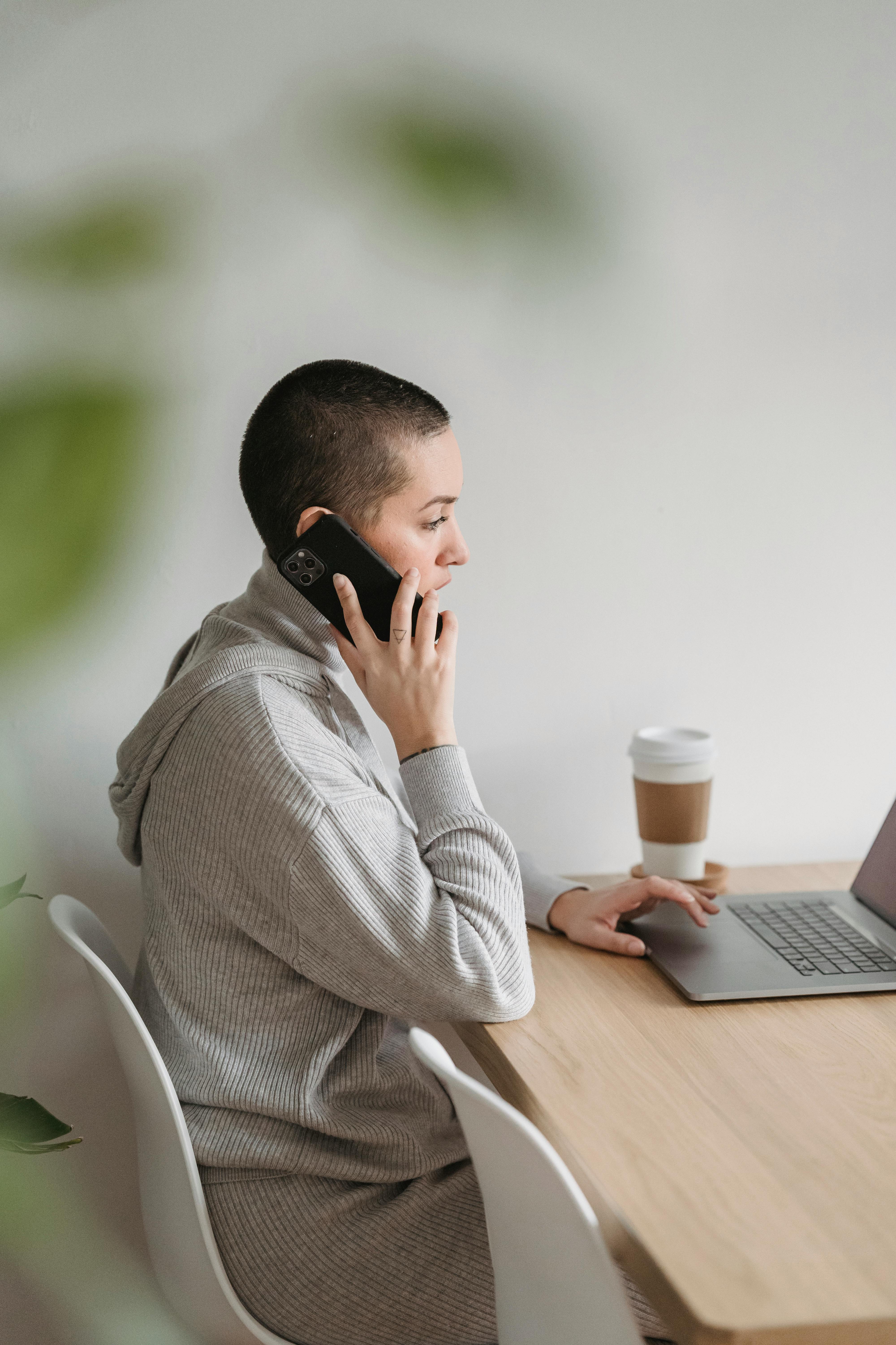 focused woman talking on phone and using laptop