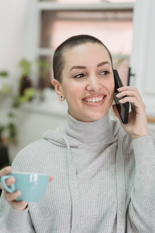 Happy woman talking on smartphone in kitchen