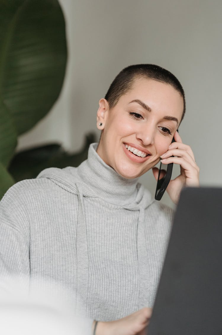 Smiling Woman Talking On Smartphone And Working On Laptop