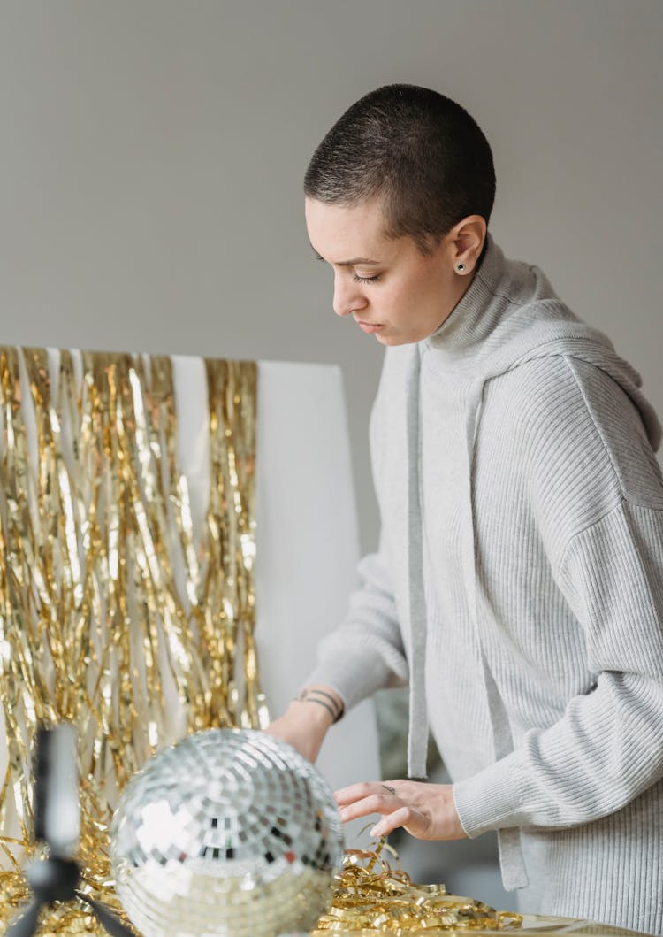 Woman In Hoodie Against Golden Tinsel And Decorative Ball Indoors