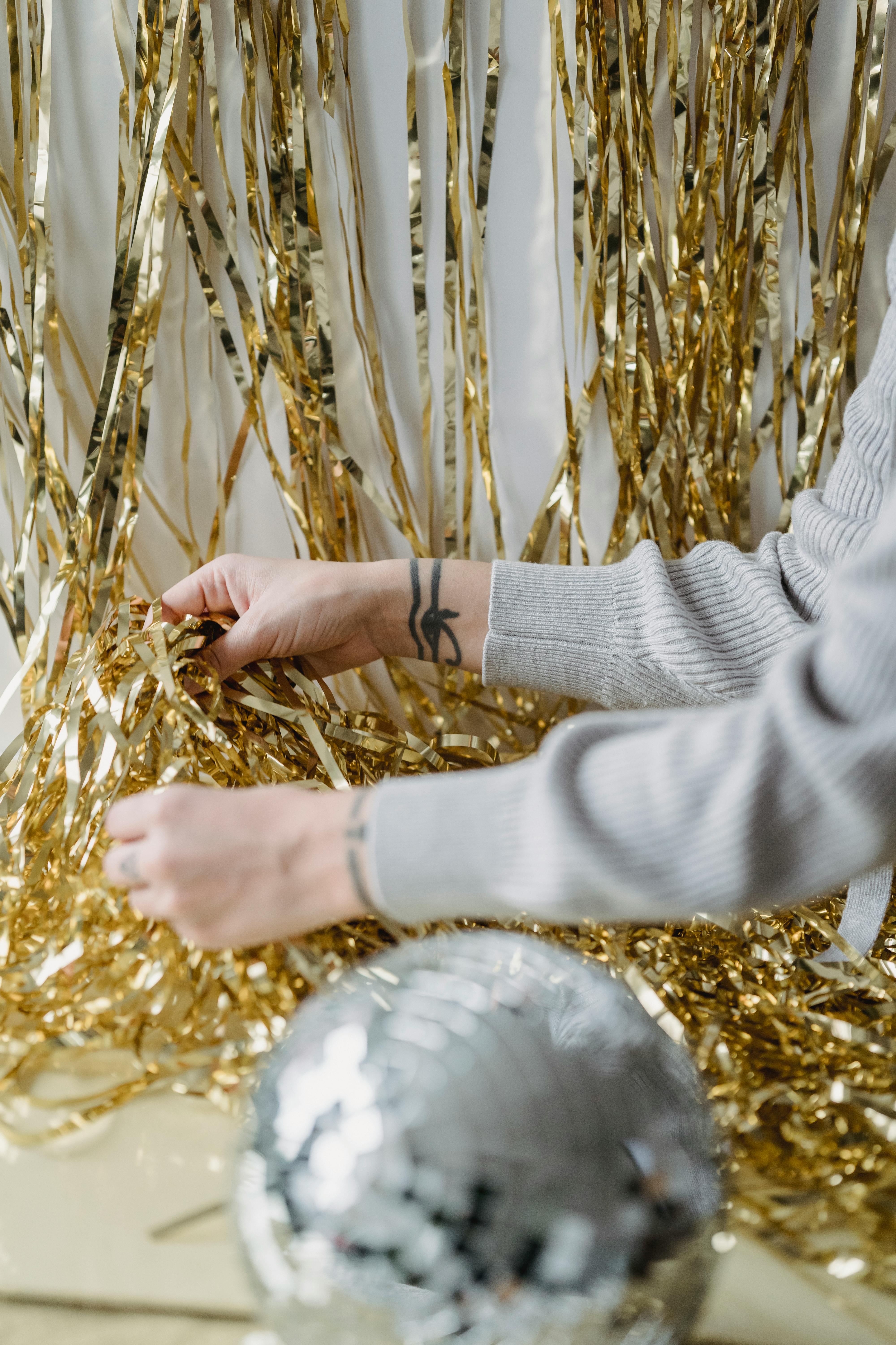 faceless tattooed person with pile of golden tinsel