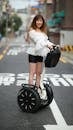 Woman in White Off Shoulder Top Riding a Segway Scooter