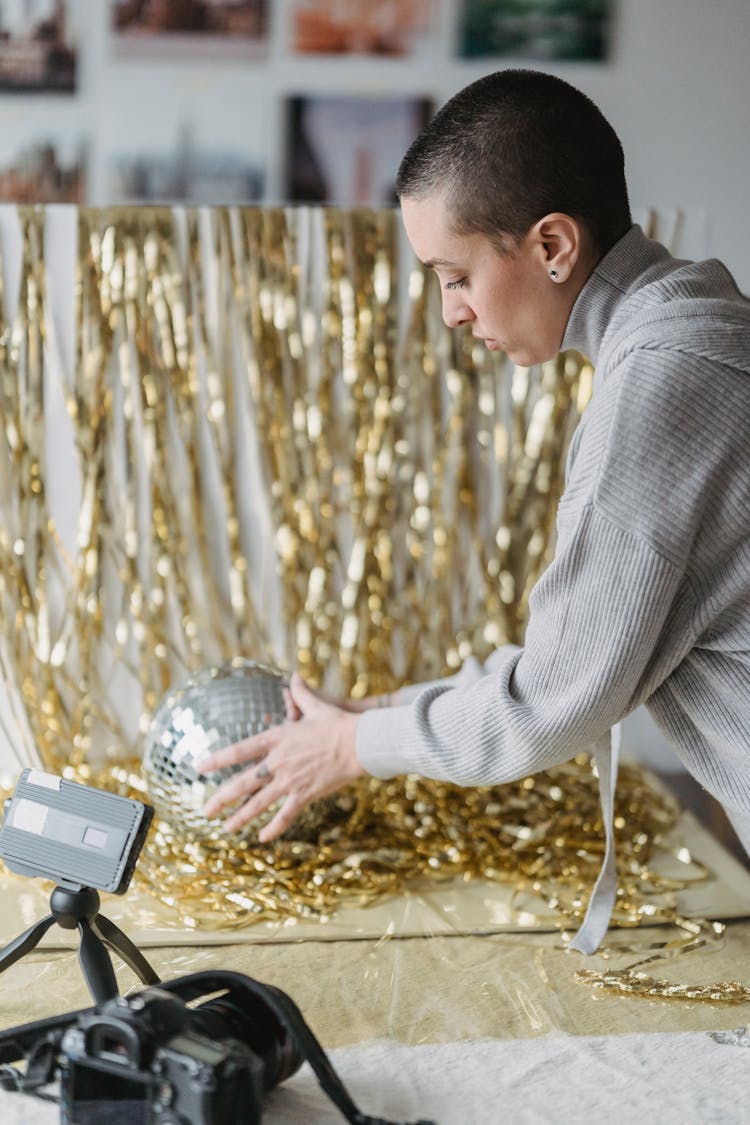 Photographer With Decorative Ball Between Photo Camera And Tinsel