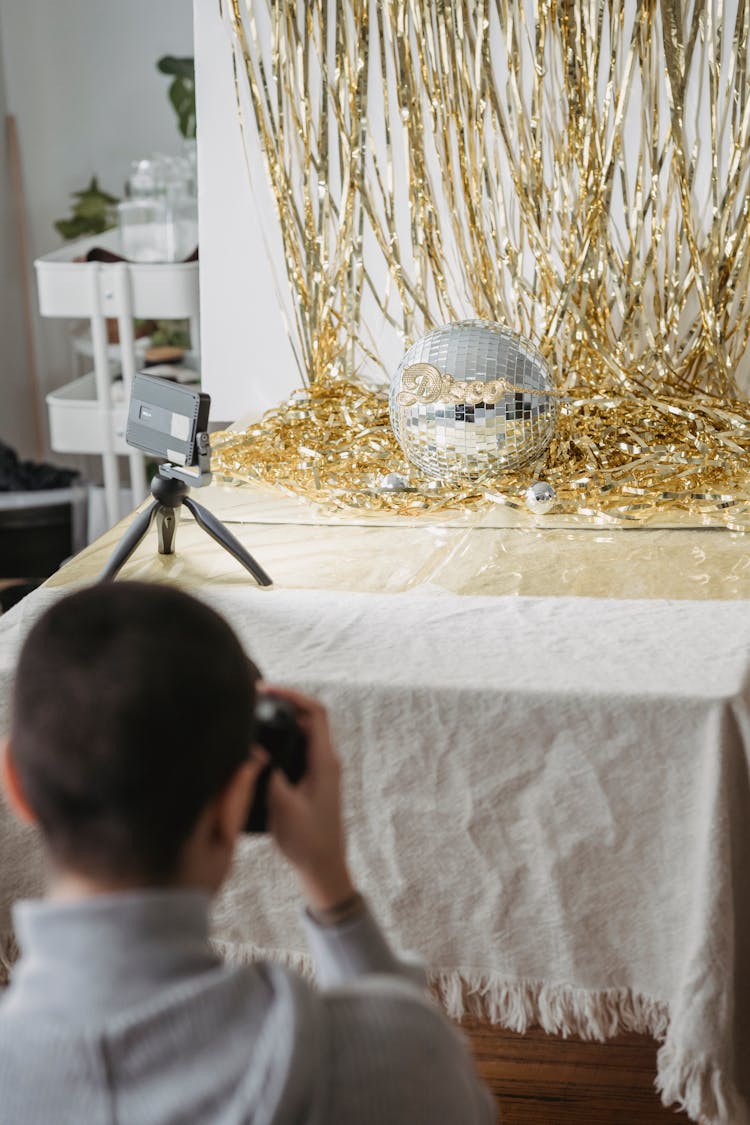 Unrecognizable Photographer Taking Photo Of Tinsel And Decorative Ball Indoors