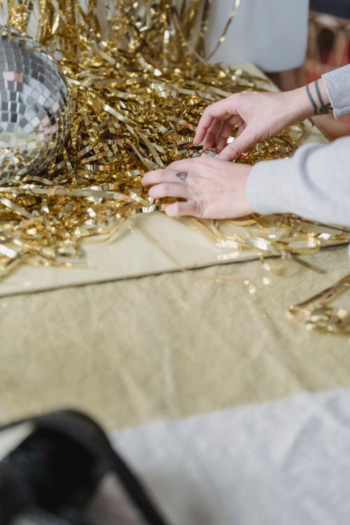 Free From above crop faceless female photographer preparing golden tinsel and disco ball for creative photo session Stock Photo
