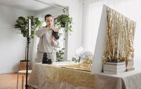 Serious woman reviewing pictures on photo camera while standing near table with golden tinsel and party ball