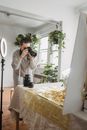 Anonymous focused female taking photo of frippery on digital camera against table with shiny lamp at home