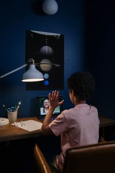 A child participates in an online class in a neatly arranged study room.