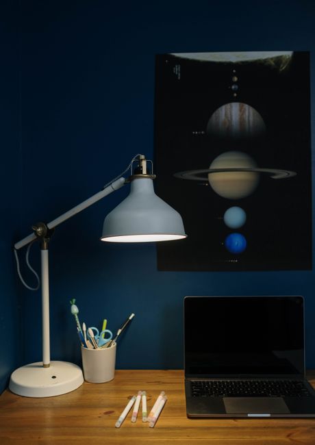 A stylish desk setup featuring a lamp, laptop, and pens, ideal for work or study in a cozy environment.