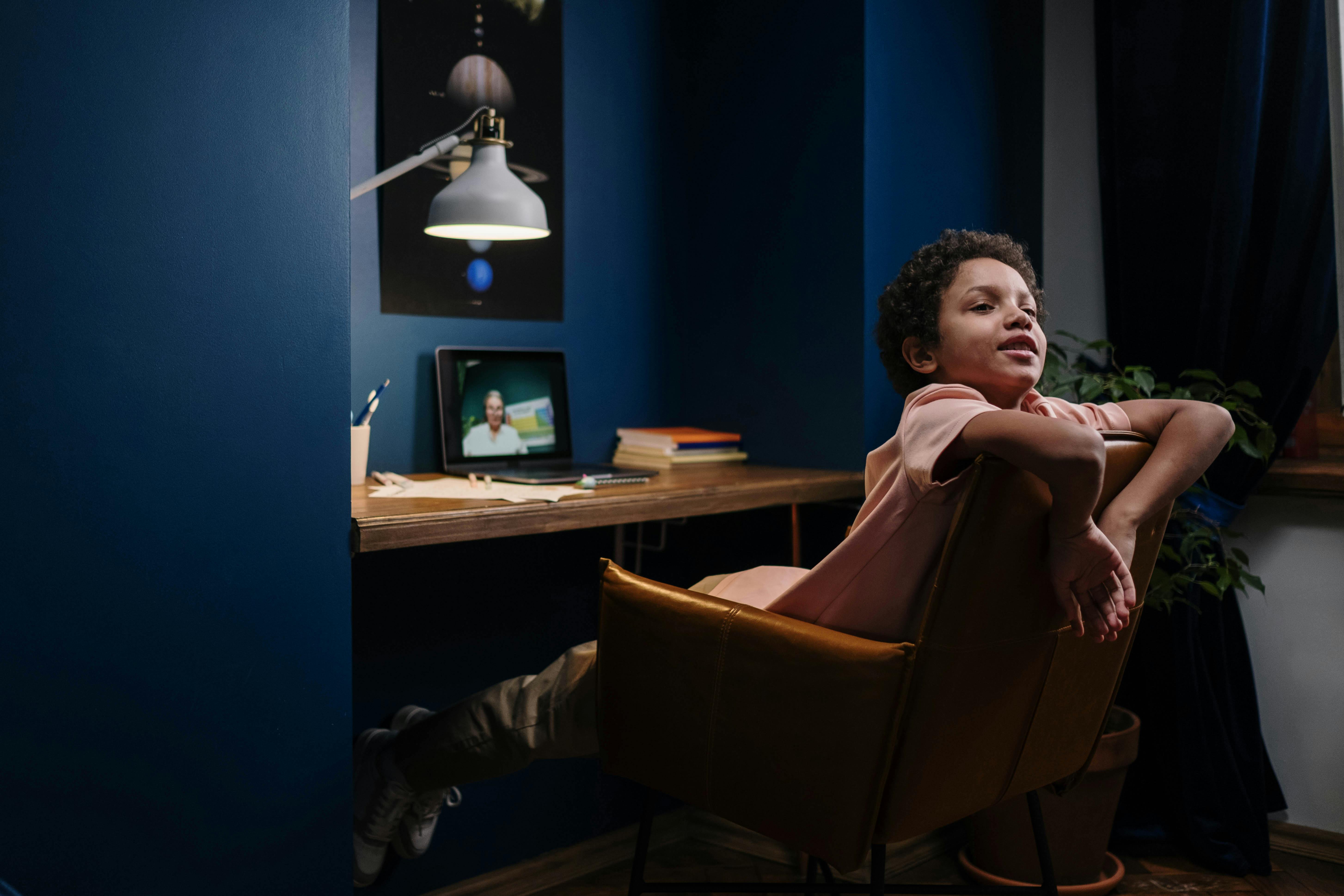 A young student relaxes while learning online in a cozy home study setup.