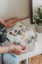 Crop unrecognizable photographer looking through printed photos in light room