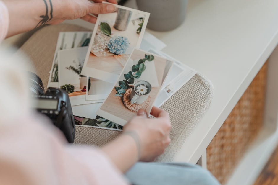 From above anonymous photographer looking through printed photos placed on white table in living room