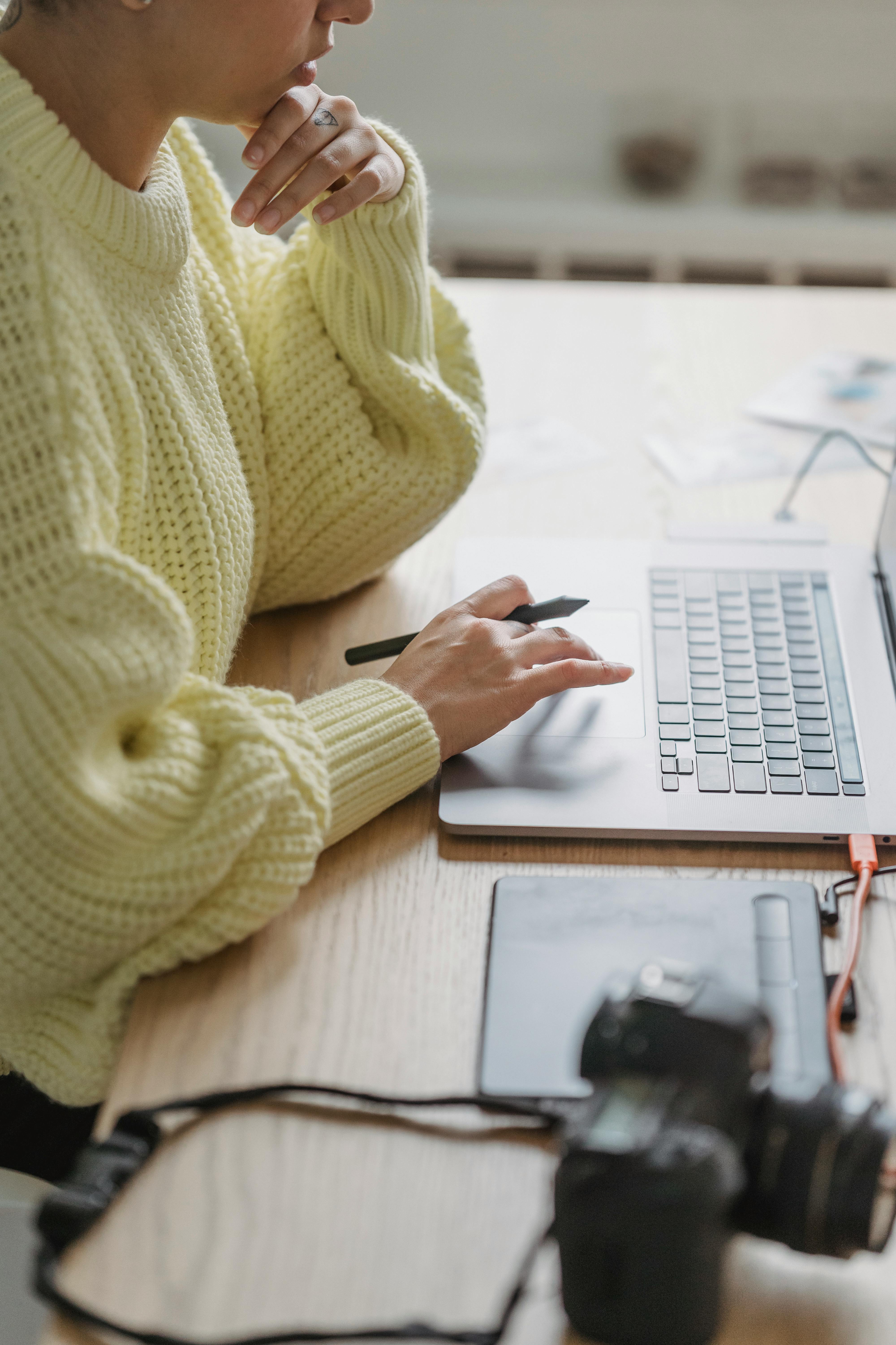 crop pensive woman working on laptop and graphic tablet