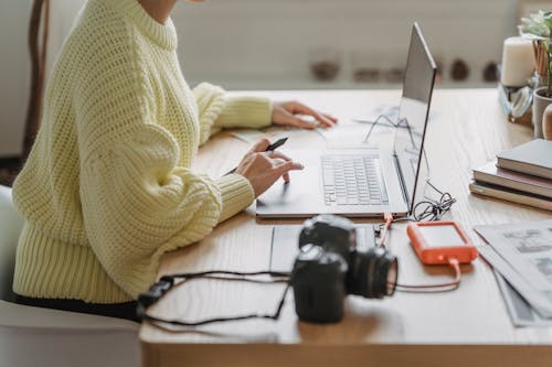 Anonymous photographer browsing laptop at table