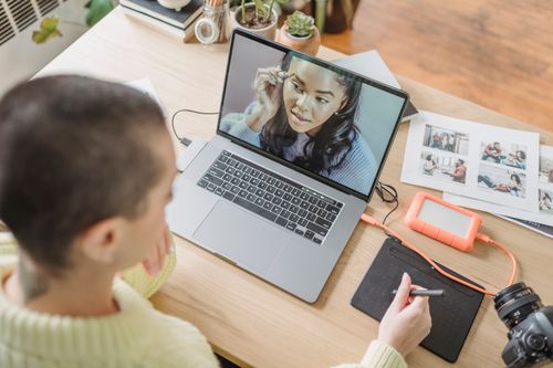 Free From above of unrecognizable female photographer with short hair using graphic tablet while retouching photo on netbook at table with photo camera Stock Photo