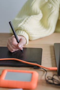 A person drawing on a digital tablet in a modern workspace, showcasing creativity and technology.