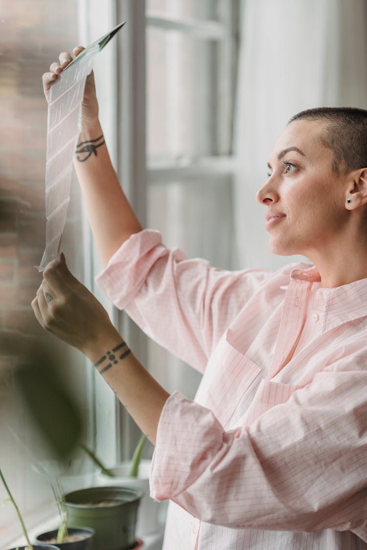 Crop Content Woman Looking At Photo Films Near Window