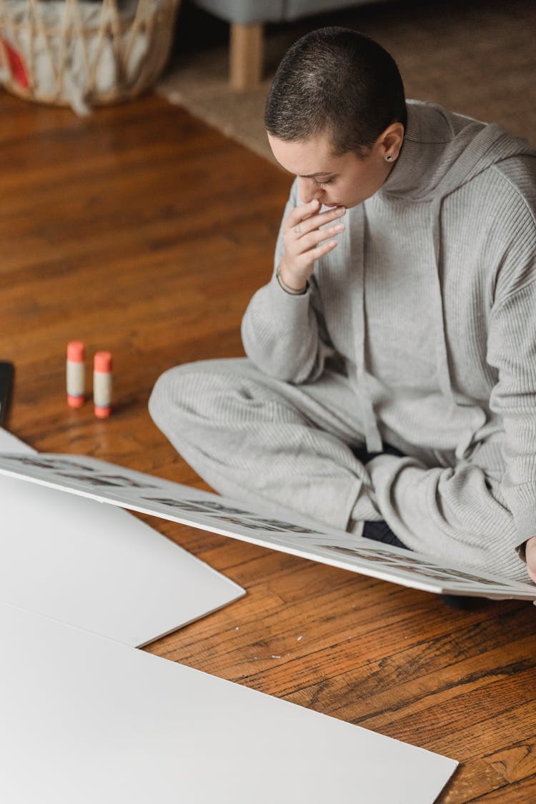 Thoughtful Woman Looking At Photo Collage On Floor