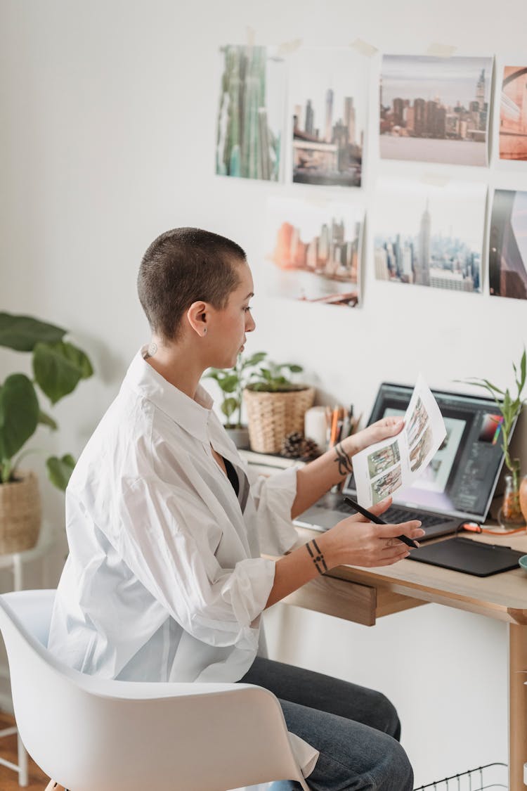 Pensive Woman Working On Laptop And Looking At Printed Photo