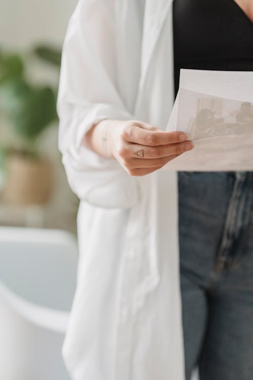 Crop faceless woman looking at printed photos