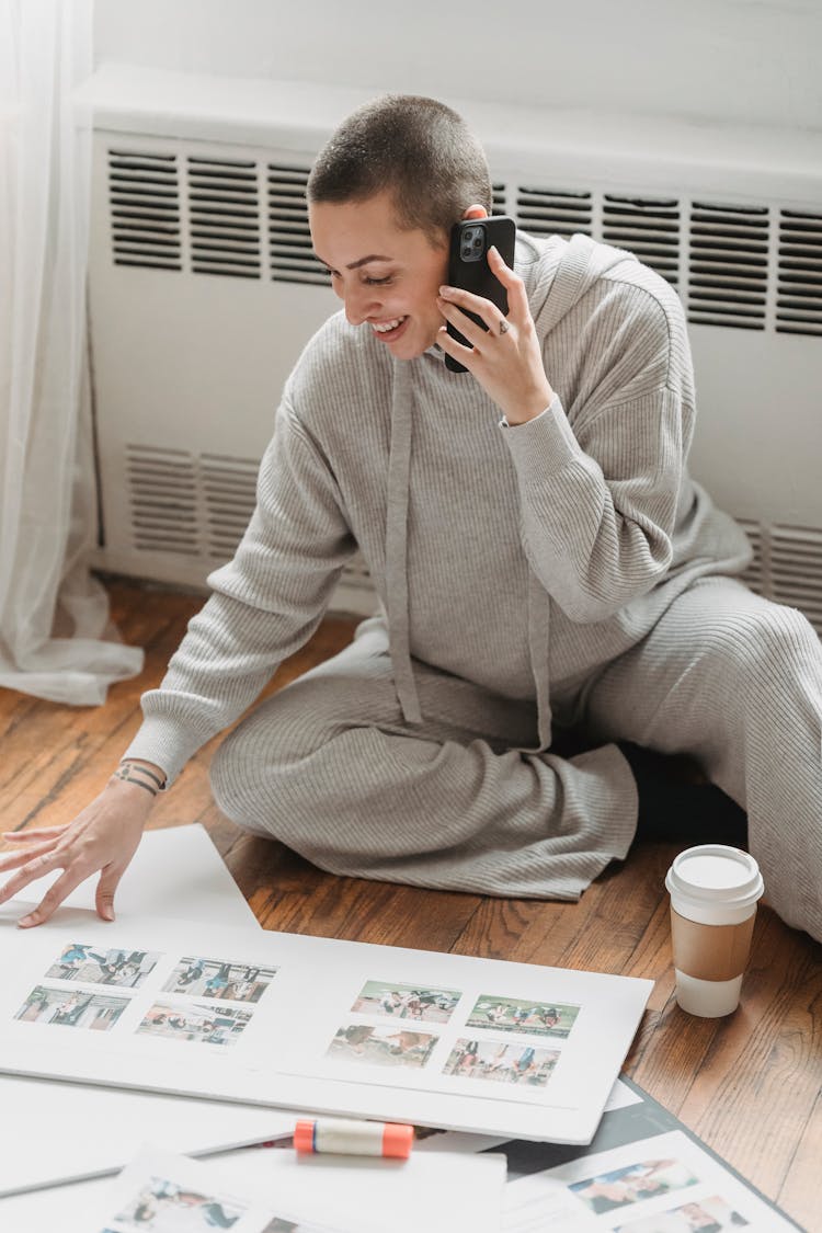 Cheerful Woman Creating Photo Album And Talking On Smartphone