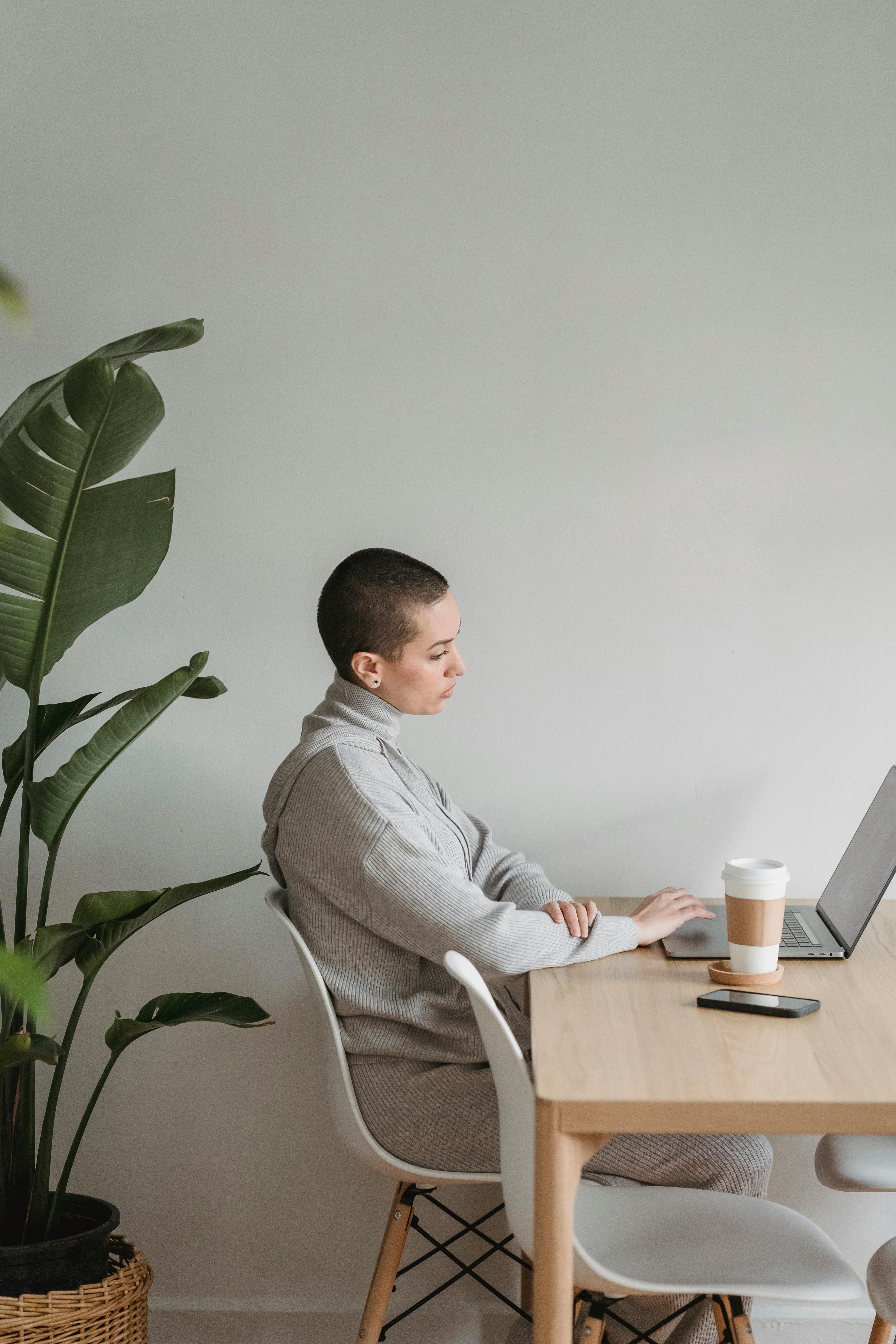 pondering woman working on modern laptop in living room