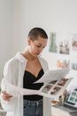 Thoughtful woman looking at printed photos in light studio