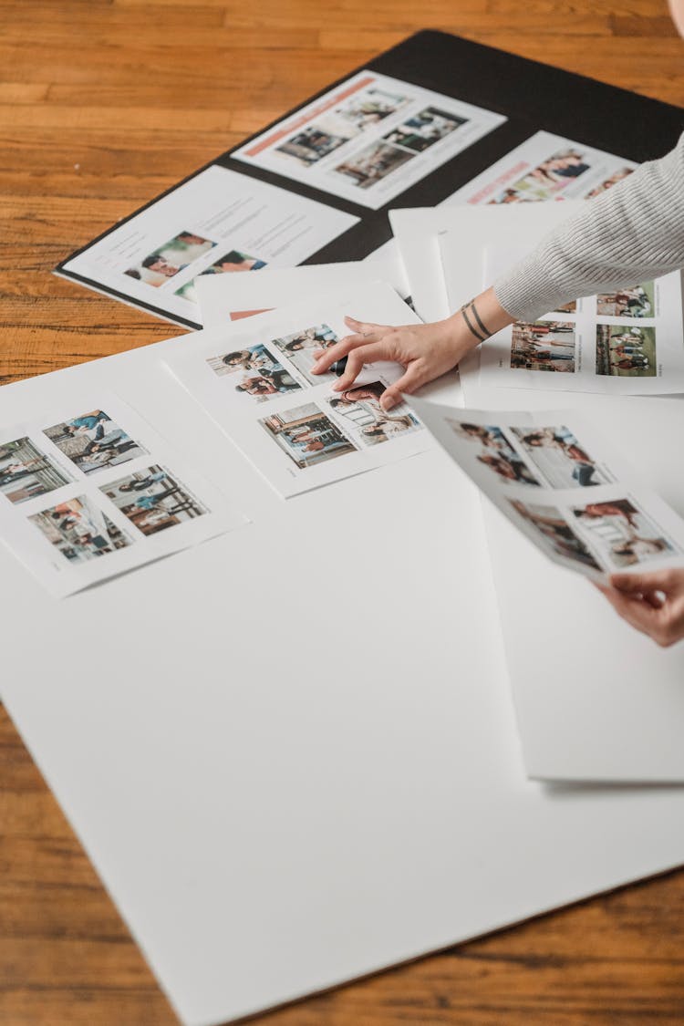 Crop Unrecognizable Person Creating Photo Collage On Floor