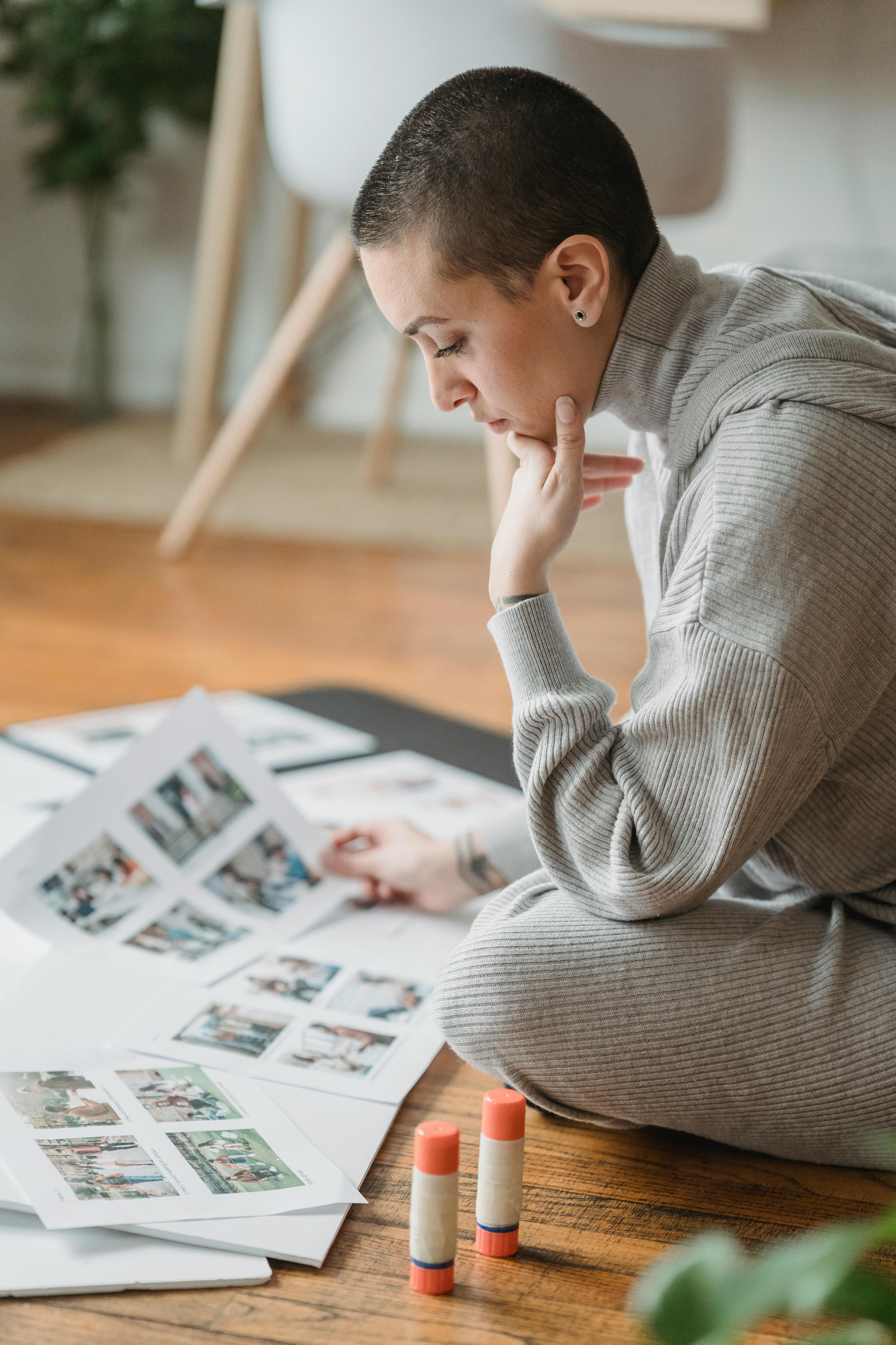 contemplative woman looking at printed photos on floor