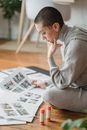 Contemplative woman looking at printed photos on floor