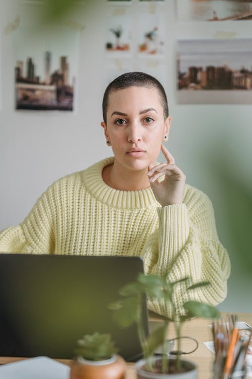 Free Female in casual clothes looking at camera while sitting at table with laptop during work Stock Photo