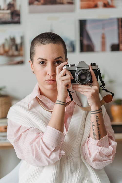 Concentrated professional female photographer taking picture on retro photo camera on blurred background