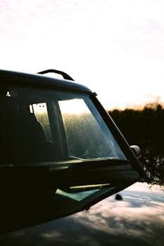 Artistic close-up of a car windshield reflecting sunset, showcasing natural beauty and automotive detail.