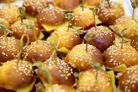 A close-up view of savory mini cheeseburger sliders topped with sesame buns, perfect for parties.