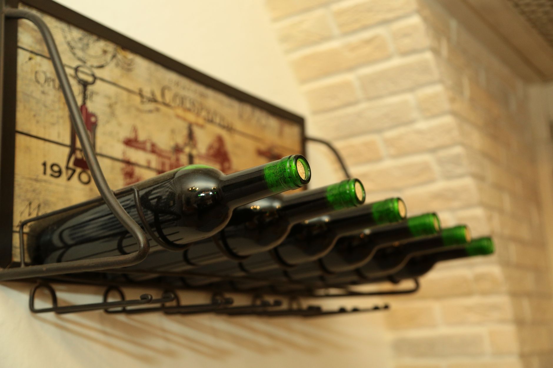 Wine bottles neatly arranged on a rack against a rustic wall, in a cozy cellar.