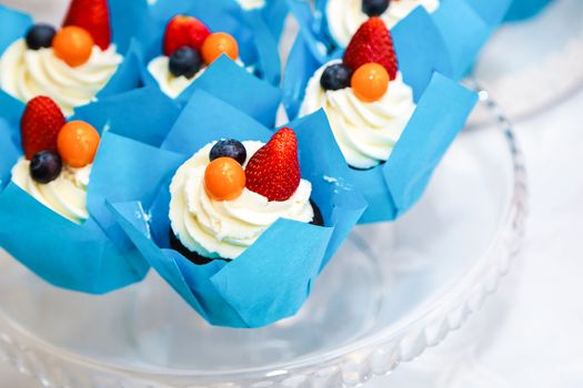 Vibrant cupcakes topped with strawberries, blueberries, and cream for a delicious treat.