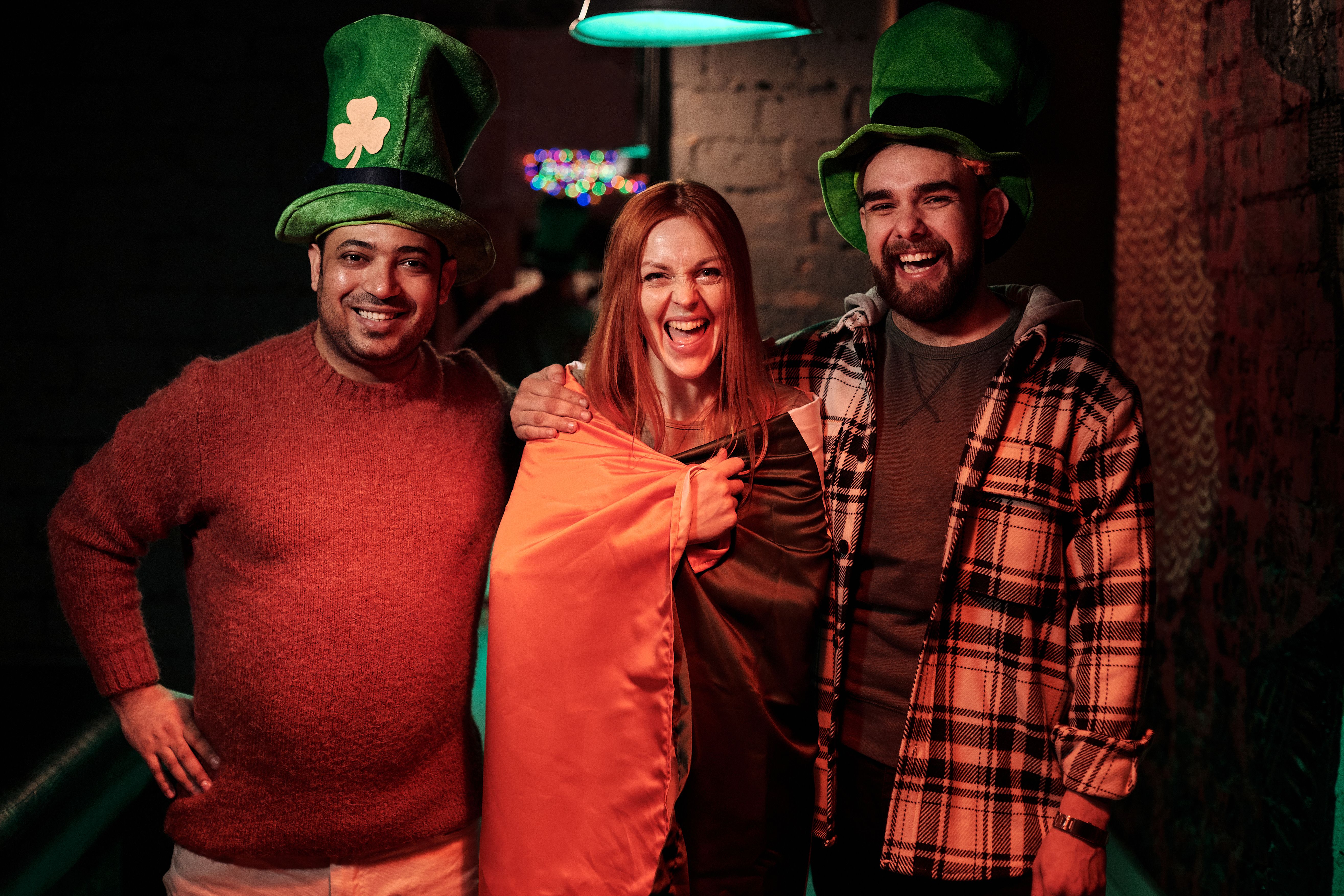 Group of friends celebrating St. Patrick's Day with joy and laughter indoors.