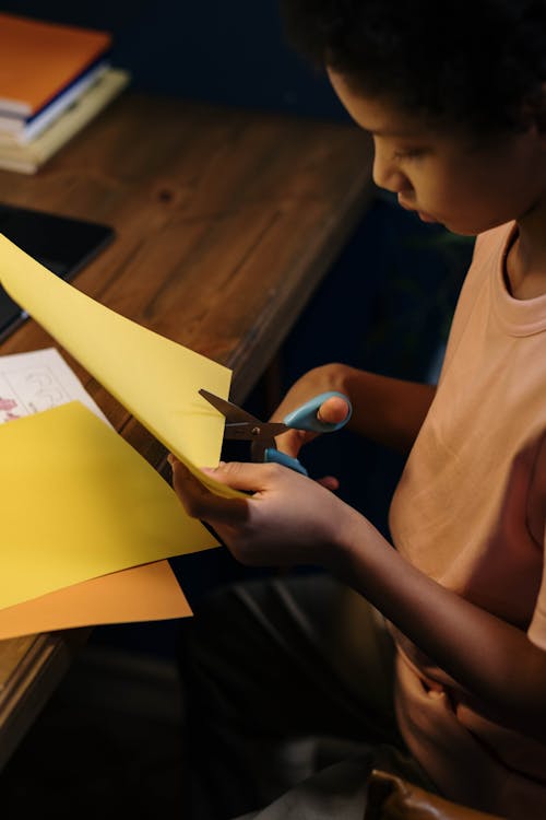 High-Angle Shot of a Child Cutting the Yellow Paper