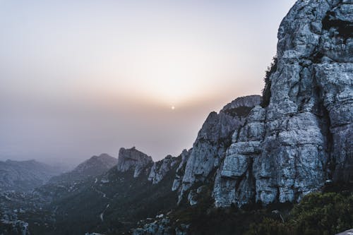 Rough rocky mountains under sun in haze