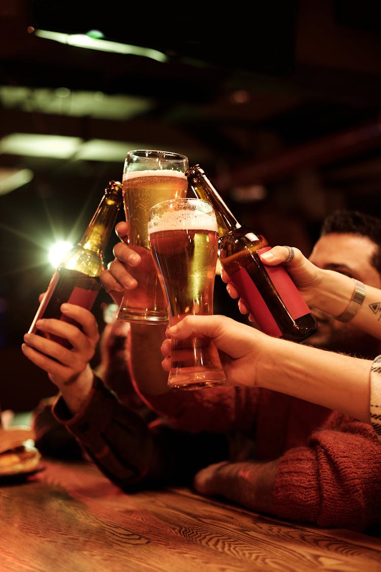 Photograph Of People Doing A Cheers With Their Beers