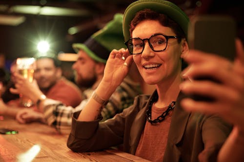 Free Shallow Focus of a Woman Wearing Eyeglasses while Taking Picture of Herself Using a Mobile Phone Stock Photo
