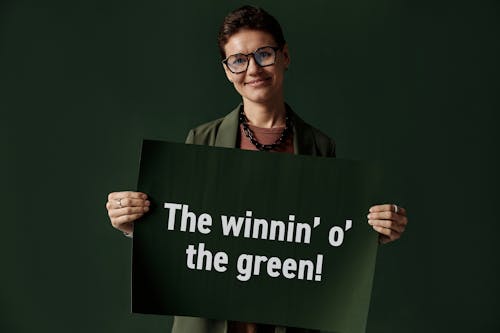 Woman Wearing Eyeglasses while Holding a Placard on Green Background