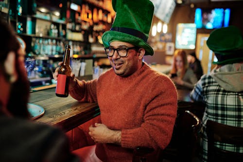 A Man Drinking in a Bar Wearing a Leprechaun Hat